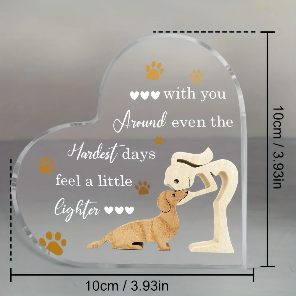 A clear freestanding acrylic heart plaque featuring a dog owner hugging a sausage dog with golden paw prints and an emotional sympathy quote on a desk next to a size dimension chart