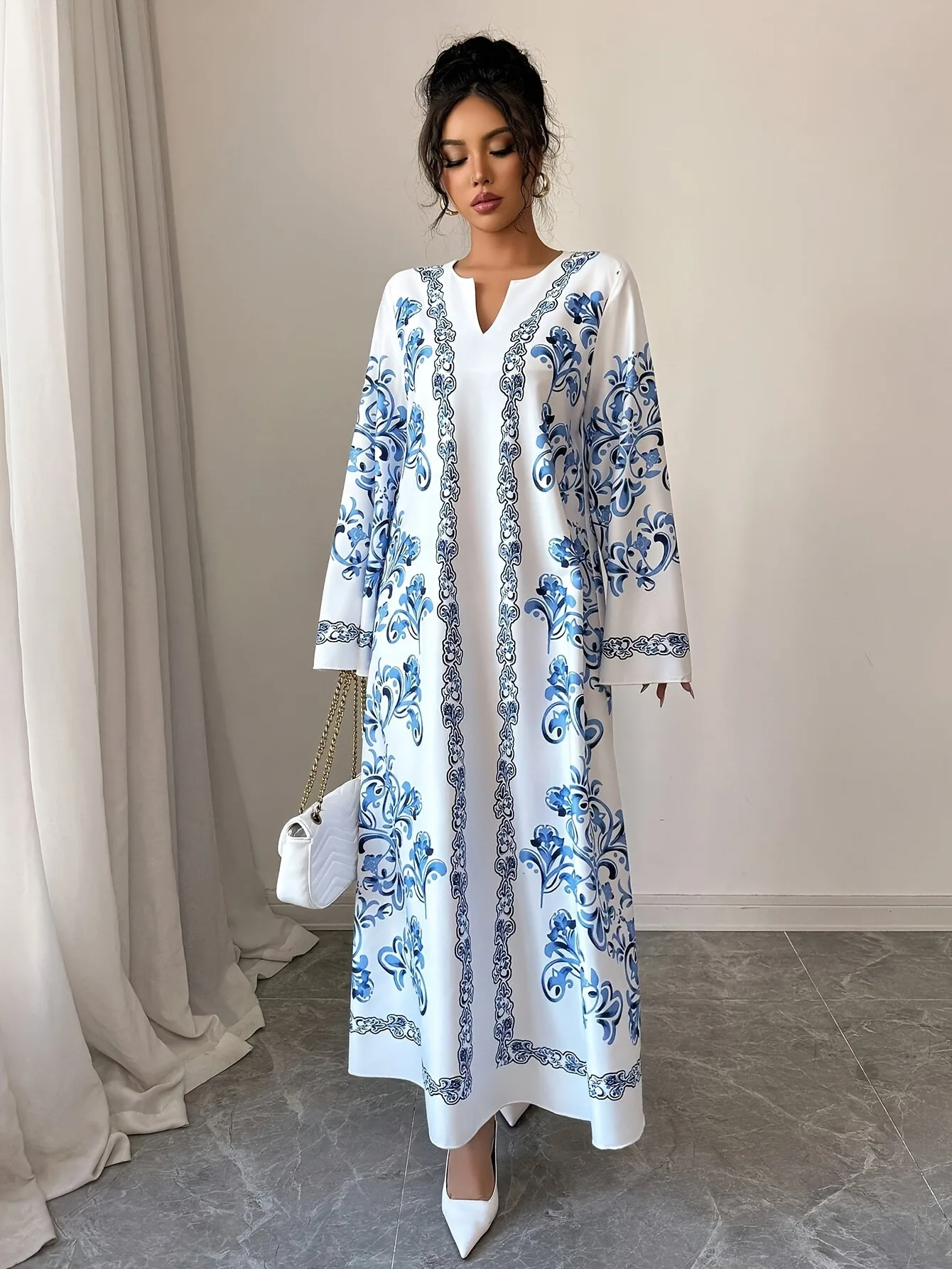 جلابية بيضاء طويلة بنقوش زرقاء وأكمام واسعة
