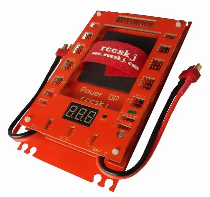 Détail du module d'alimentation double batterie 12 canaux pour drone FPV, interrupteur électronique et CDI intégré, avec étiquettes de spécifications et bornes de connexion.