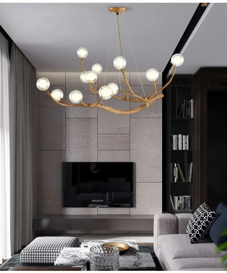 A modern living room with the Branch Pendant Light, featuring glass orb shades, a TV on a stone wall, a patterned rug, and a sleek gray sofa captures the essence of organic modern lighting.