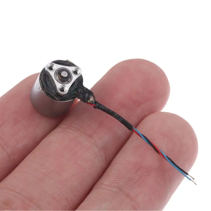 Gros plan sur micro moteur électrique métal 1.2x1cm argent, câbles de connexion soudés aux broches.