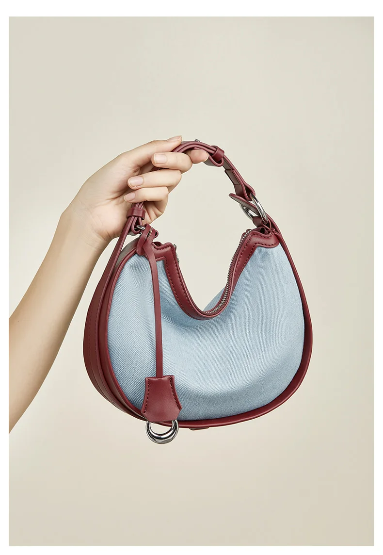 Woman carrying half moon shoulder bag made of denim with genuine leather trim – casual and stylish design for daily use.