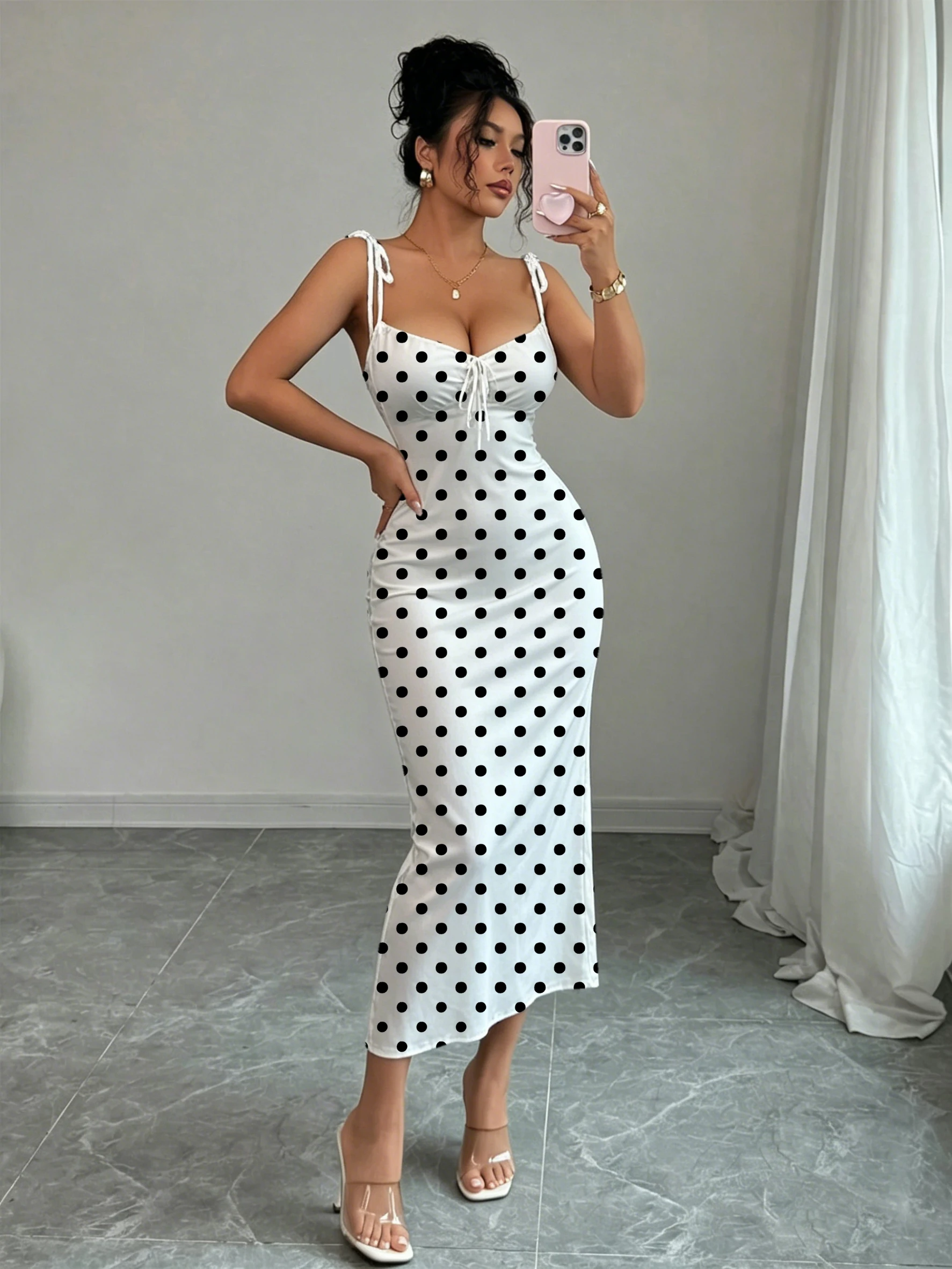 Robe sirène noire à pois sur fond blanc, avec double nœud papillon aux épaules et fronces sur la poitrine pour une mise en valeur de la taille, coupe ajustée, moulante aux hanches, longueur mi-longue