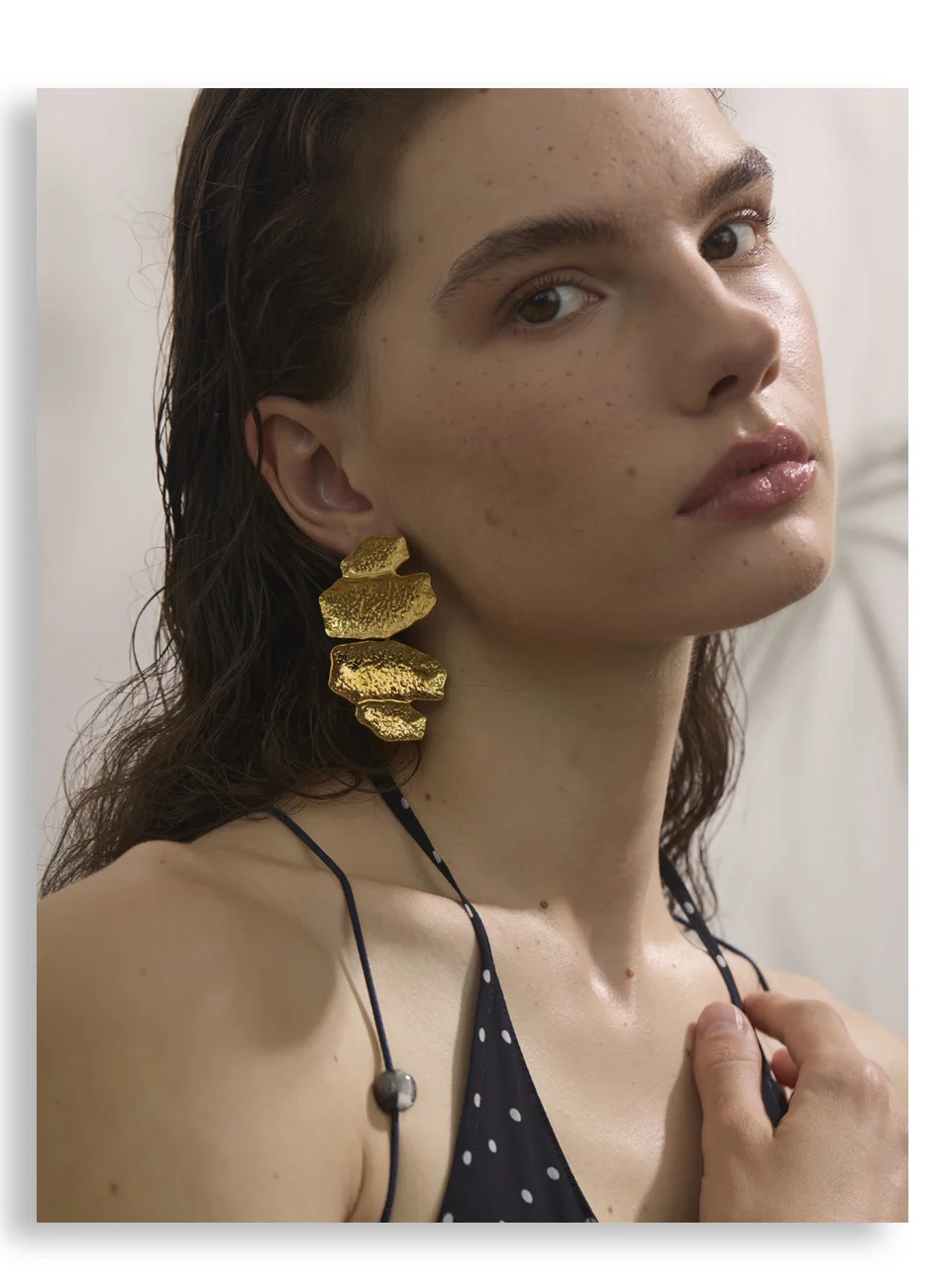 Woman wearing gold earrings with a neutral background sold by Poised Me Jewelry Studio