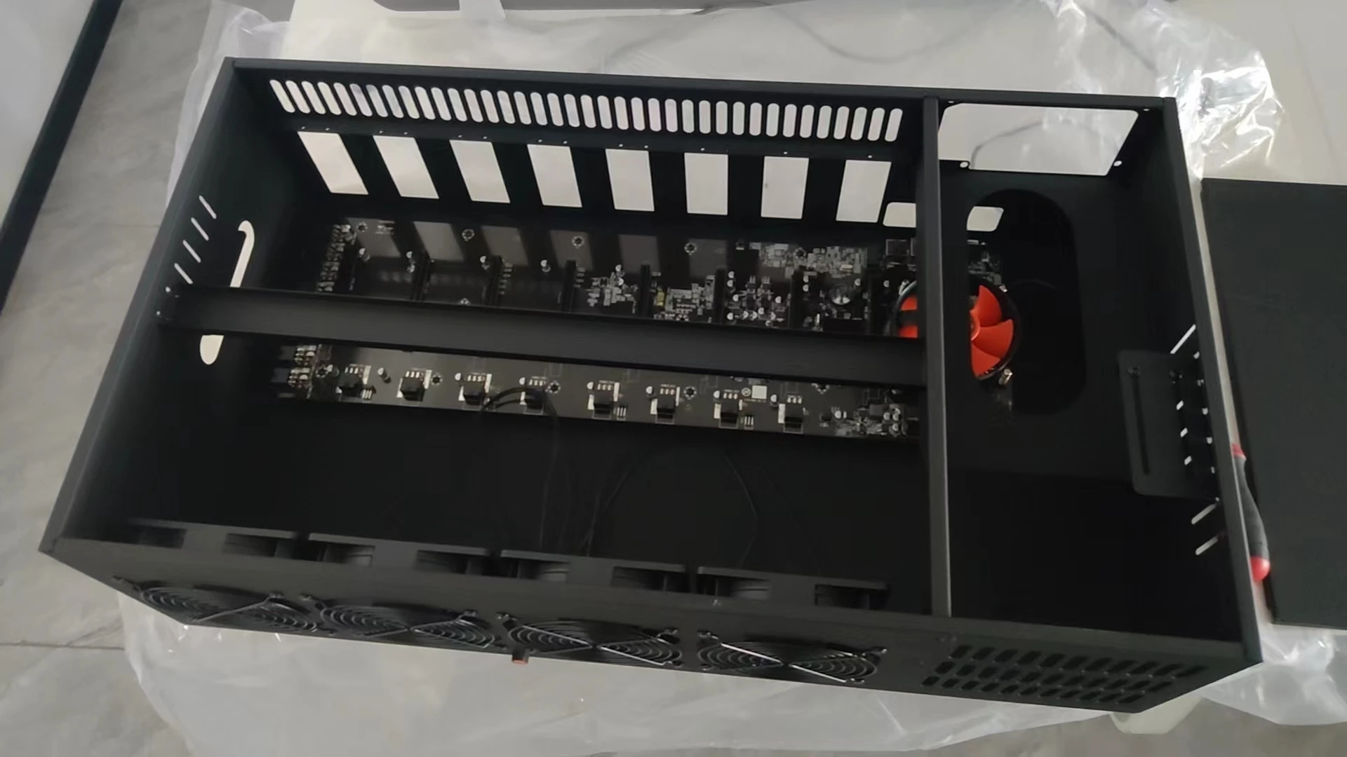 A set of eight PCI card slots in a miner's chassis. The mainboard model is ETH B85 V2.11. There is one fan on the mainboard