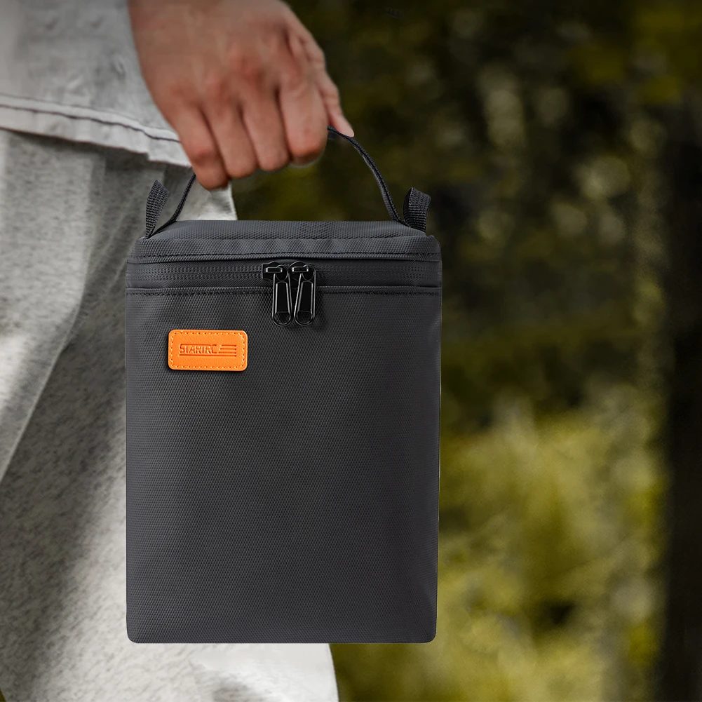 Sac chauffe-batterie drone USB étanche noir porté à l'épaule par une personne, câble USB branché sur une power bank.