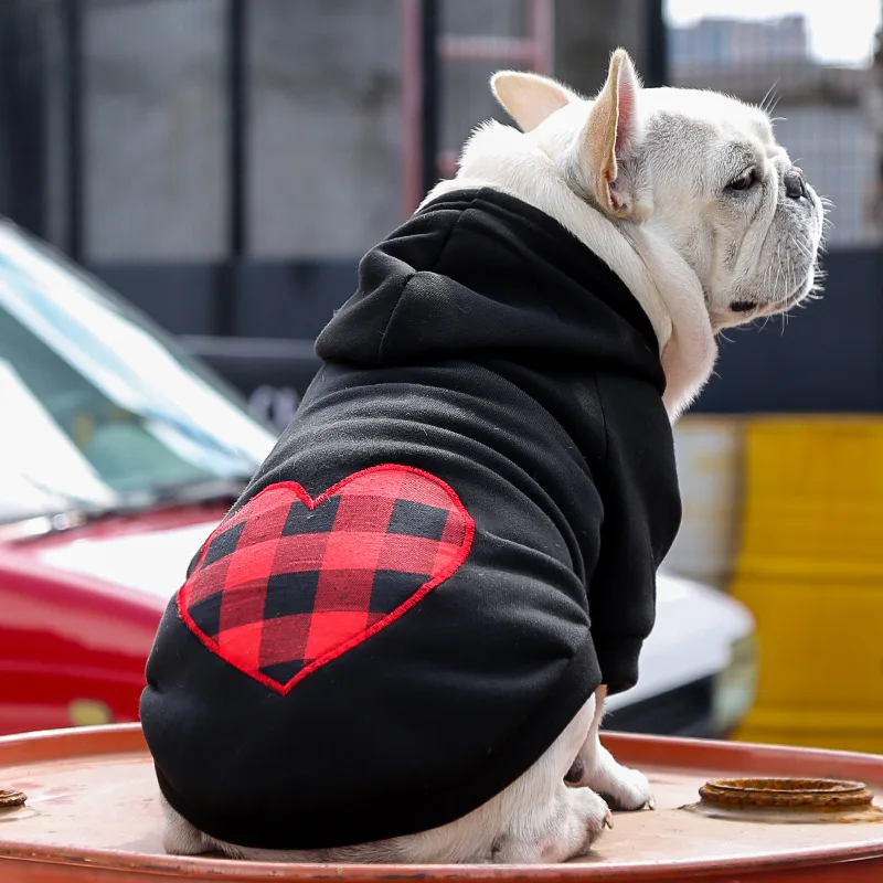 A dog wearing a plaid hoodie with a heart on its back.