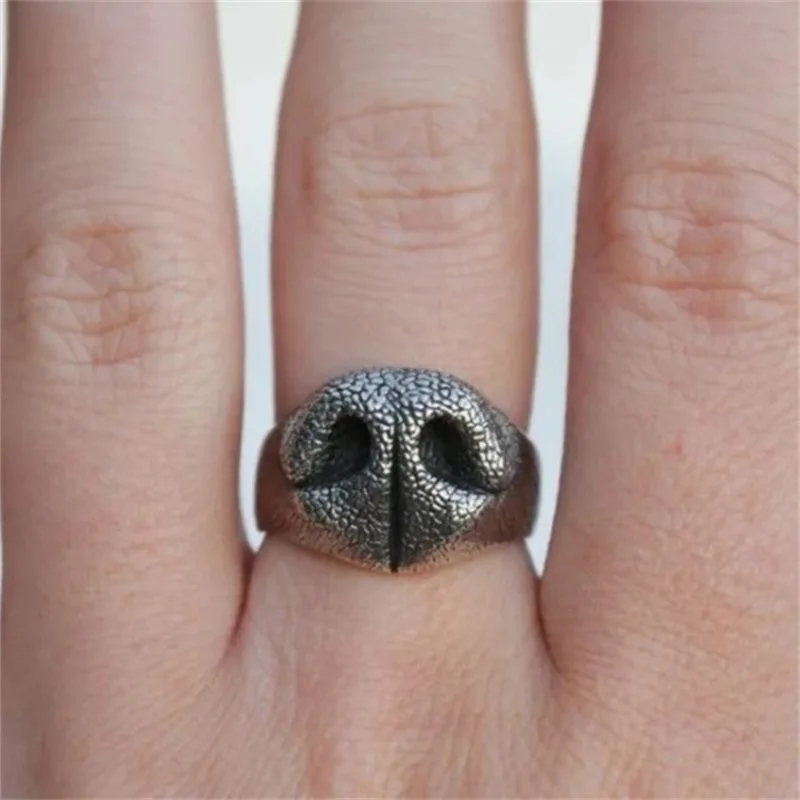 Close up view of a silver plated chunky ring shaped like a detailed dog nose worn on a finger