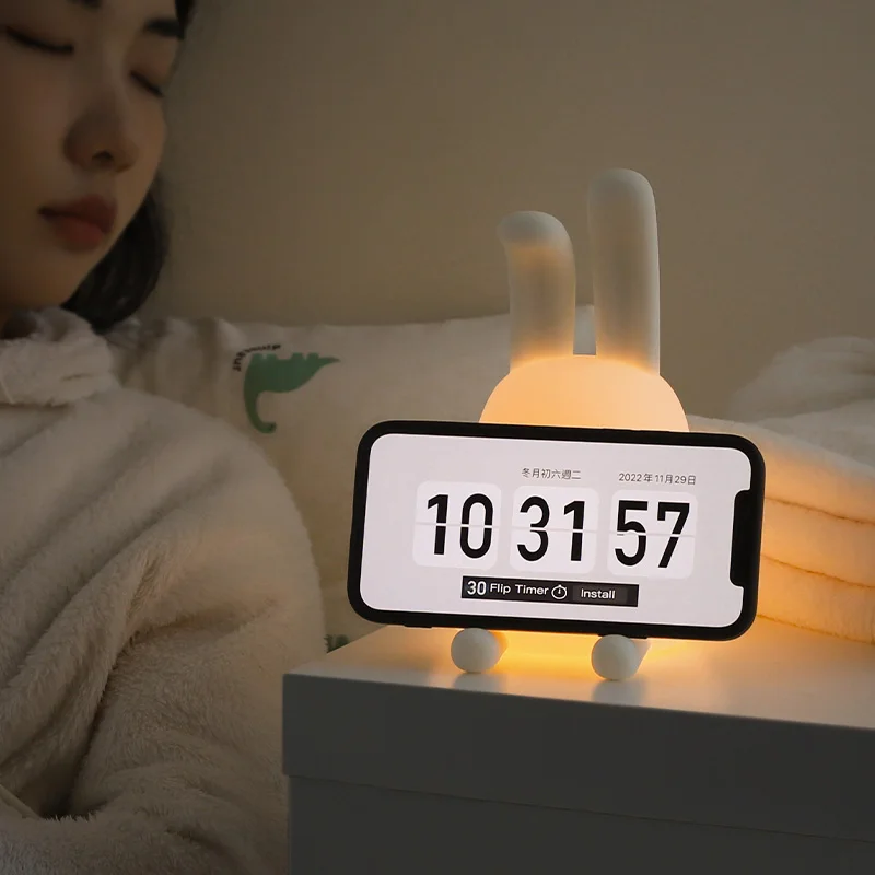 A woman with a phone next to an adorable bunny touch lamp.